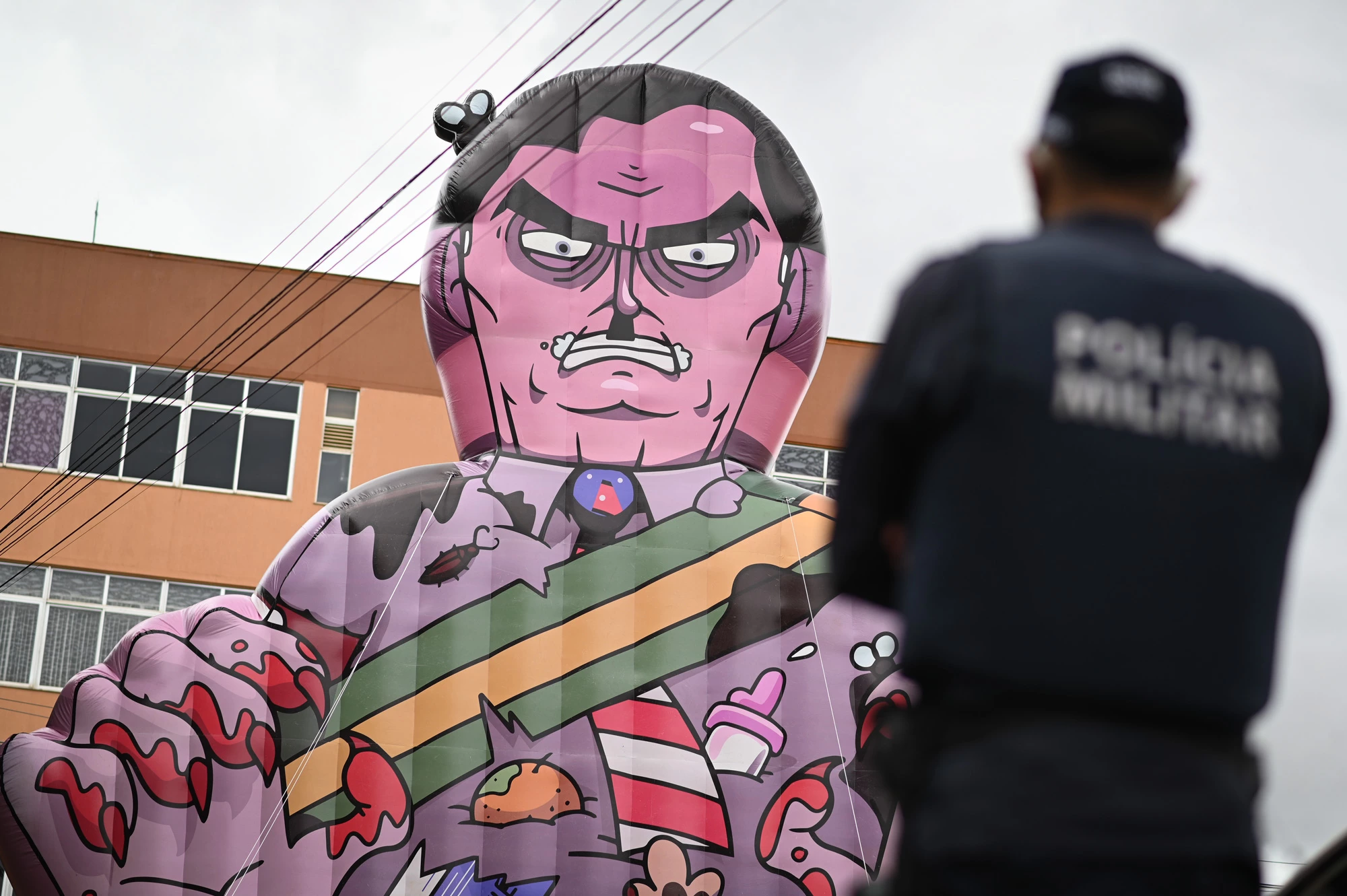 BRASILIA, BRAZIL - JANUARY 17: A police officer watches a large puppet representing Brazil's President Jair Bolsonaro as a killer raised by demonstrators during a protest in favor of Bolsonaro's impeachment in front of the headquarters of Brazil's health agency ANVISA (National Health Surveillance Agency) amidst the Coronavirus (COVID - 19) pandemic on January 17, 2021 in Brasilia. Brazil has over 8.455,000 confirmed positive cases of Coronavirus and has over 209,296 deaths. (Photo by Andre Borges/Getty Images)