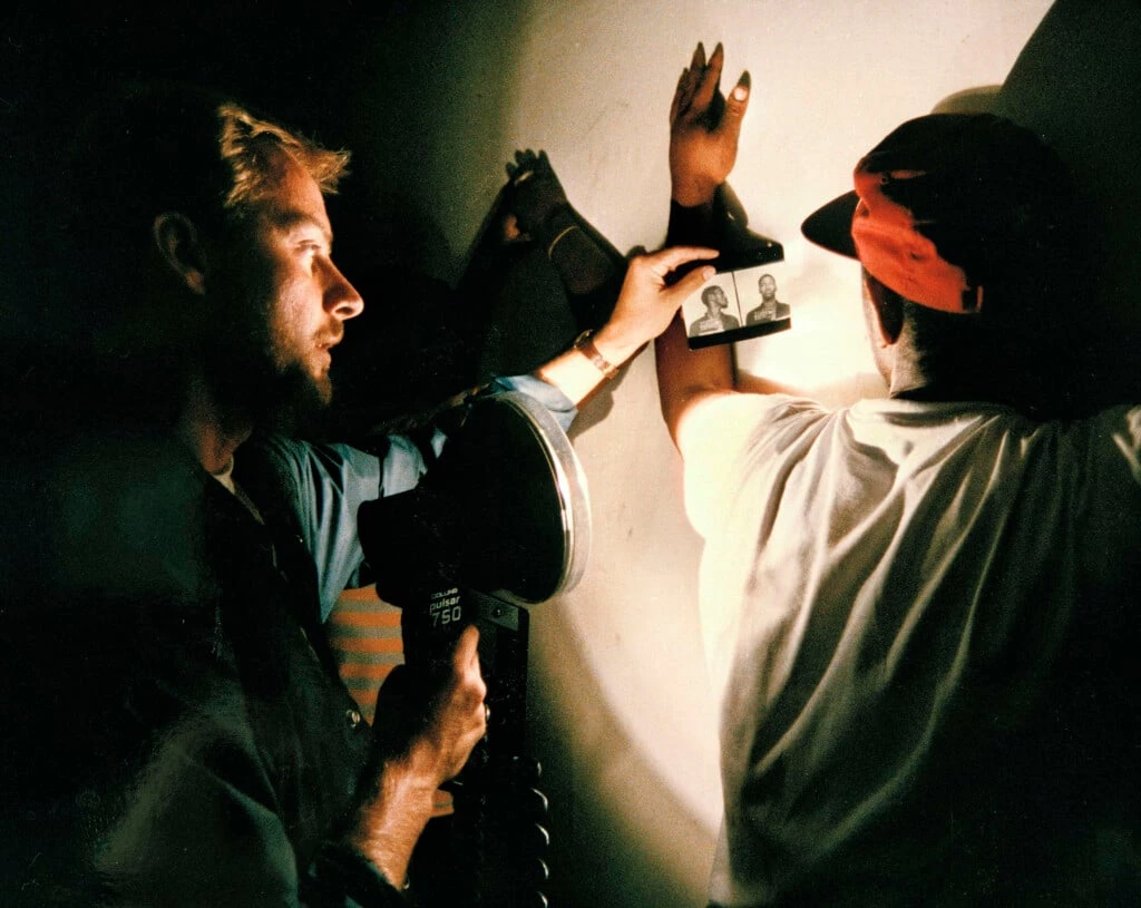 Um oficial de justiça, à esquerda, mostra uma foto de um suspeito a um homem que, segundo a polícia, fora encontrado usando drogas em um ponto de venda de entorpecentes em Washington, D.C., no dia 18 de julho de 1989. A operação fazia parte da “guerra às drogas” do então presidente dos EUA, George H. W. Bush.