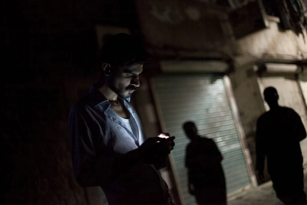 Homem sírio olha para o seu celular no bairro de Bustan al-Qasr, em Aleppo, Síria, em 21 de setembro de 2012.