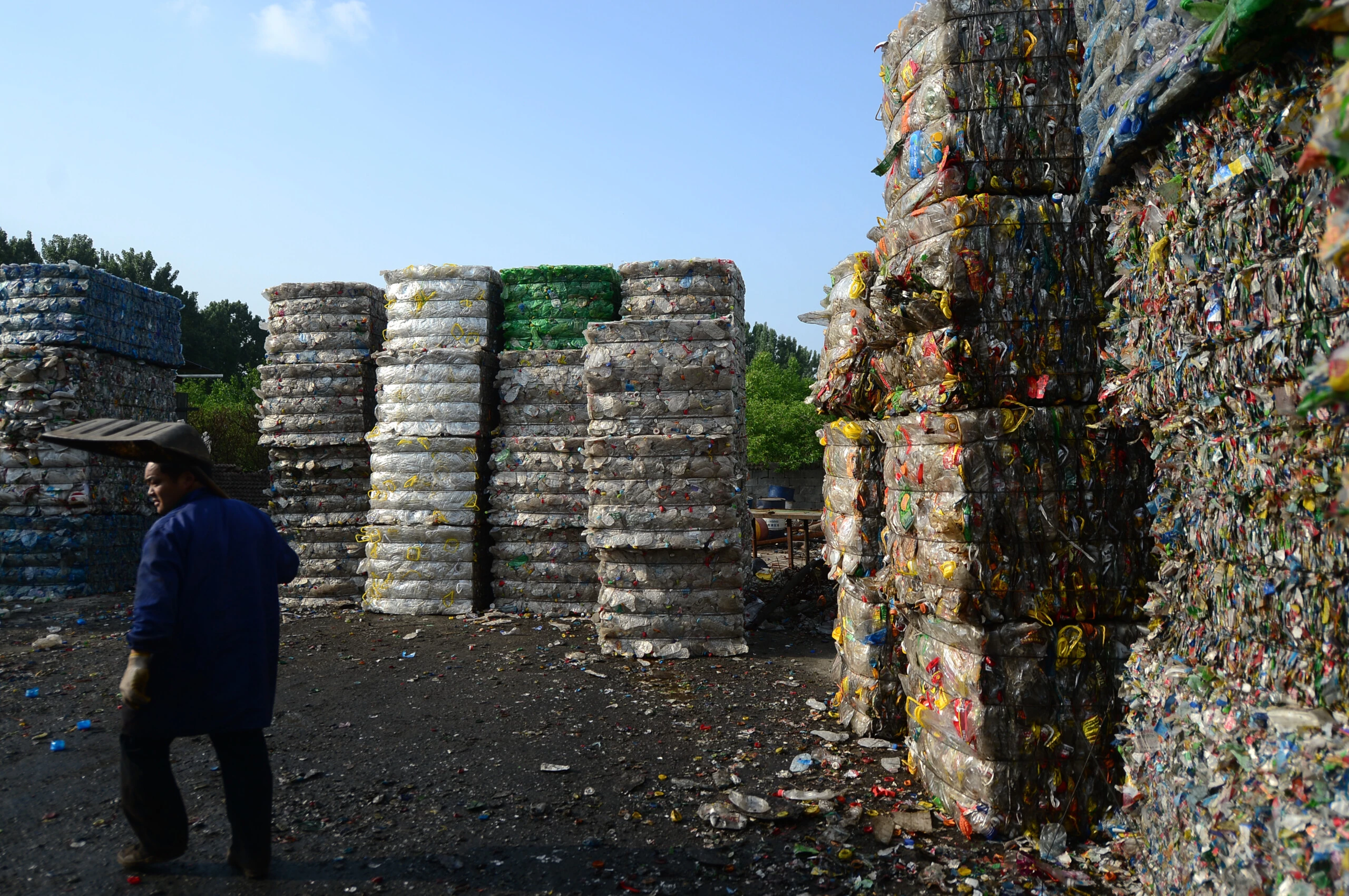 Um trabalhador chinês passa por pilhas de garrafas plásticas em uma estação de reciclagem na cidade de Ji'nan, na província de Shandong, no leste da China, em 4 de maio de 2017.