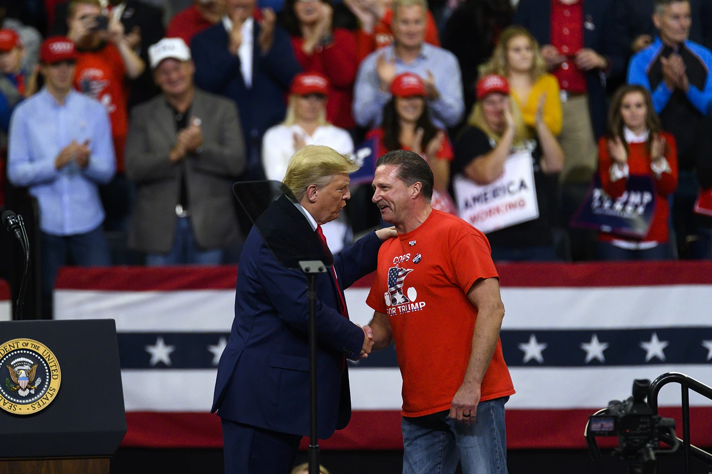 O presidente Donald Trump aperta a mão do chefe do Sindicato de Policiais de Minneapolis, tenente Bob Kroll, no palanque durante um comício de campanha no Target Center em 10 de outubro de 2019, em Minneapolis.