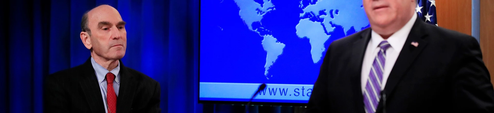 Elliott Abrams, esquerda, escuta o Secretário de Estado Mike Pompeo falar sobre a Venezuela no Departamento de Estado, em Washington, D.C., em 25 de janeiro de 2019. Elliott Abrams, esquerda, escuta o Secretário de Estado Mike Pompeo falar sobre a Venezuela no Departamento de Estado, em Washington, D.C., em 25 de janeiro de 2019.