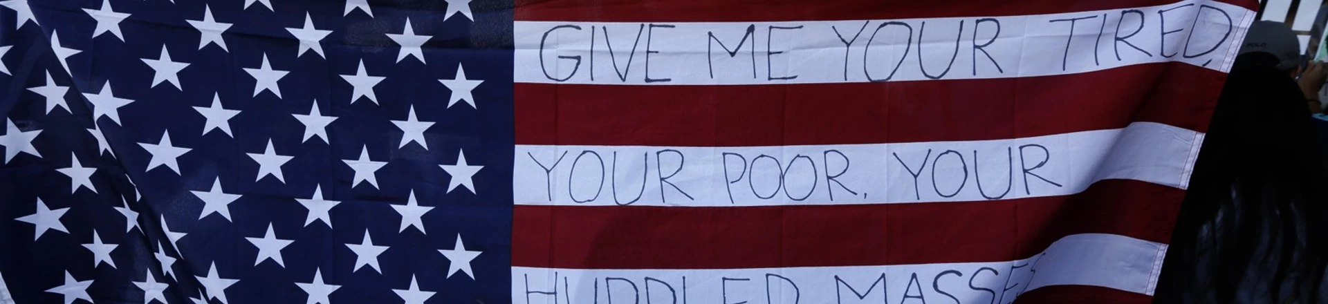 LOS ANGELES, CA - JANUARY 29: Chella, from Sherman Oaks, holds the U.S. flag with words from the sonnet, "The New Colossus," by poet Emma Lazarus while joining people who continue to protest President Donald Trump's travel ban at the Tom Bradley International Terminal at LAX on January 29, 2017 in Los Angeles, California. The poem is attached to the Statue of Liberty. Chella only goes by her first name. (Photo by Genaro Molina / LA Times via Getty Images) LOS ANGELES, CA - JANUARY 29: Chella, from Sherman Oaks, holds the U.S. flag with words from the sonnet, "The New Colossus," by poet Emma Lazarus while joining people who continue to protest President Donald Trump's travel ban at the Tom Bradley International Terminal at LAX on January 29, 2017 in Los Angeles, California. The poem is attached to the Statue of Liberty. Chella only goes by her first name. (Photo by Genaro Molina / LA Times via Getty Images)
