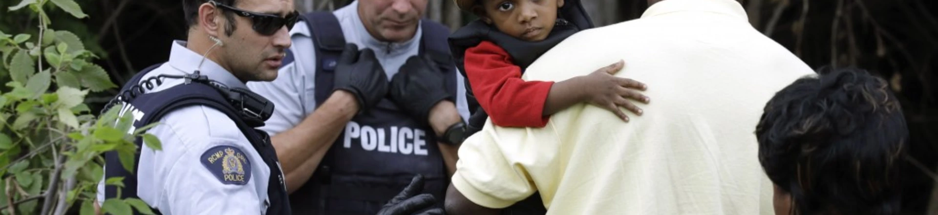 A Haitian boy holds onto his father as they approach an illegally crossing point, staffed by Royal Canadian Mounted Police officers, from Champlain, N.Y., to Saint-Bernard-de-Lacolle, Quebec, Monday, Aug. 7, 2017. Seven days a week, 24-hours a day people from across the globe are arriving at the end of a New York backroad so they can walk across a ditch into Canada knowing they will be instantly arrested, but with the hope the Canadian government will be kinder to them than the United States. (AP Photo/Charles Krupa) A Haitian boy holds onto his father as they approach an illegally crossing point, staffed by Royal Canadian Mounted Police officers, from Champlain, N.Y., to Saint-Bernard-de-Lacolle, Quebec, Monday, Aug. 7, 2017. Seven days a week, 24-hours a day people from across the globe are arriving at the end of a New York backroad so they can walk across a ditch into Canada knowing they will be instantly arrested, but with the hope the Canadian government will be kinder to them than the United States. (AP Photo/Charles Krupa)