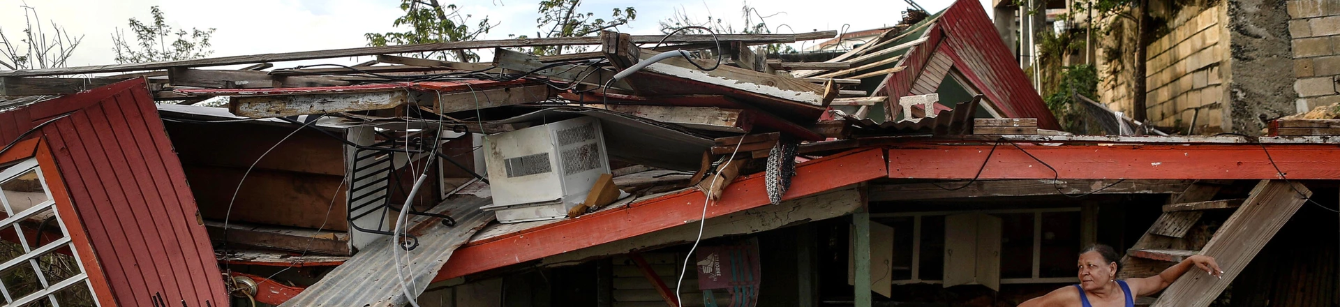 SAN ISIDRO, PUERTO RICO - OCTOBER 17: Gladys Francisco stands in front of her destroyed home after U.S. soldiers unloaded food and water, provided by FEMA, to residents in the neighborhood still without grid electricity or running water on October 17, 2017 in San Isidro, Puerto Rico. The food and water delivery mission included U.S. Army, U.S. Coast Guard and Puerto Rico Hacienda forces. Residents said this was the first official governmental delivery of food and water to the community, nearly four weeks after the hurricane hit. Puerto Rico is suffering shortages of food and water in areas and only 17.7 percent of grid electricity has been restored. Puerto Rico experienced widespread damage including most of the electrical, gas and water grid as well as agriculture after Hurricane Maria, a category 4 hurricane, swept through. (Photo by Mario Tama/Getty Images) SAN ISIDRO, PUERTO RICO - OCTOBER 17: Gladys Francisco stands in front of her destroyed home after U.S. soldiers unloaded food and water, provided by FEMA, to residents in the neighborhood still without grid electricity or running water on October 17, 2017 in San Isidro, Puerto Rico. The food and water delivery mission included U.S. Army, U.S. Coast Guard and Puerto Rico Hacienda forces. Residents said this was the first official governmental delivery of food and water to the community, nearly four weeks after the hurricane hit. Puerto Rico is suffering shortages of food and water in areas and only 17.7 percent of grid electricity has been restored. Puerto Rico experienced widespread damage including most of the electrical, gas and water grid as well as agriculture after Hurricane Maria, a category 4 hurricane, swept through. (Photo by Mario Tama/Getty Images)
