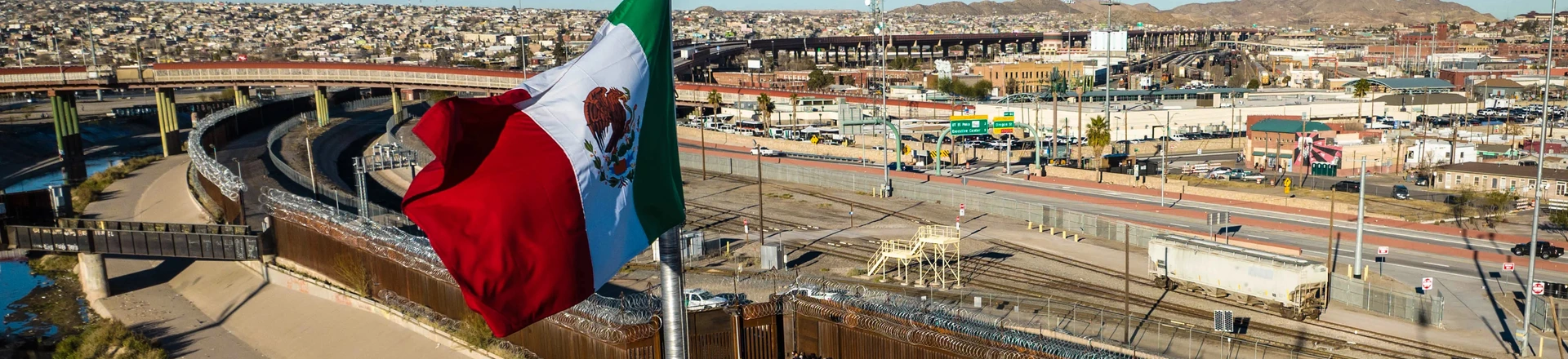 Vista aérea da bandeira do México sobre uma ponte internacional enquanto migrantes chegam à cerca da fronteira Estados Unidos para buscar asilo em 2022. Vista aérea da bandeira do México sobre uma ponte internacional enquanto migrantes chegam à cerca da fronteira Estados Unidos para buscar asilo em 2022.